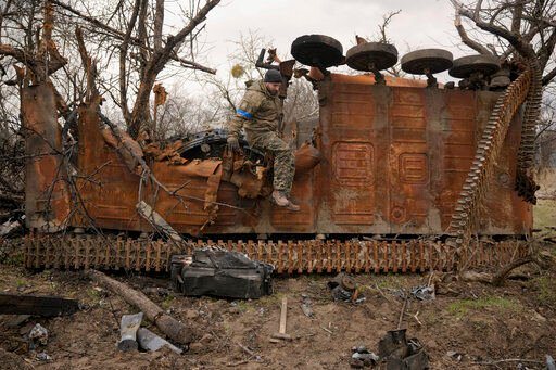 A Ukrainian serviceman jumps from a destroyed Russian fighting vehicle after collecting parts and ammunition in the village of Andriivka, Ukraine, heavily affected by fighting between Russian and Ukrainian forces, Wednesday, April 6, 2022. Several buildings in the village were reduced to mounds of bricks and corrugated metal and residents struggle without heat, electricity or cooking gas. (AP Photo/Vadim Ghirda)    PHOTO CREDIT: Vadim Ghirda