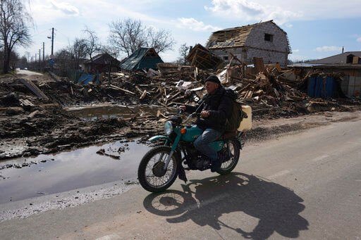 A man rides a motorbike past a house damaged by shelling in Chernihiv, Ukraine, Thursday, April 7, 2022. Ukraine is telling residents of its industrial heartland to leave while they still can after Russian forces withdrew from the shattered outskirts of Kyiv to regroup for an offensive in the country