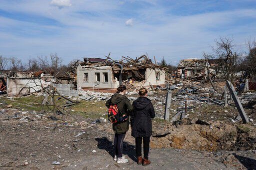 Women look at houses damaged by shelling in Chernihiv, Ukraine, Thursday, April 7, 2022. Ukraine is telling residents of its industrial heartland to leave while they still can after Russian forces withdrew from the shattered outskirts of Kyiv to regroup for an offensive in the country