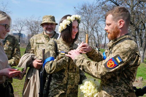 Vyacheslav, a Ukrainian soldier, puts a wedding ring on Anastasia