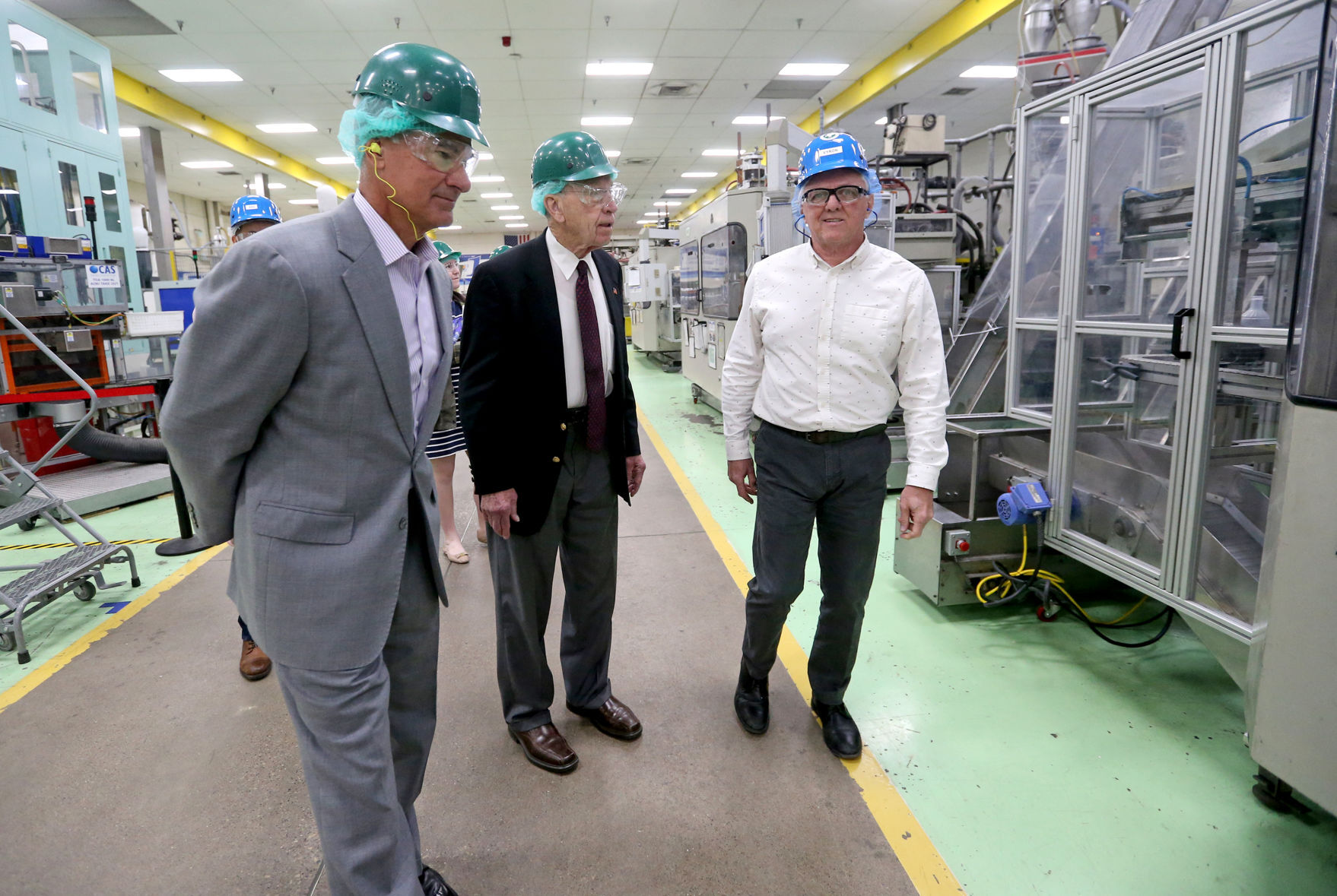 Tom Salmon (far left), president and CEO at Berry Plastics, and Vyron Nelson (far right), plant manager at Berry Plastics, speak with U.S. Sen. Chuck Grassley (left), R-Iowa, during a tour of the company