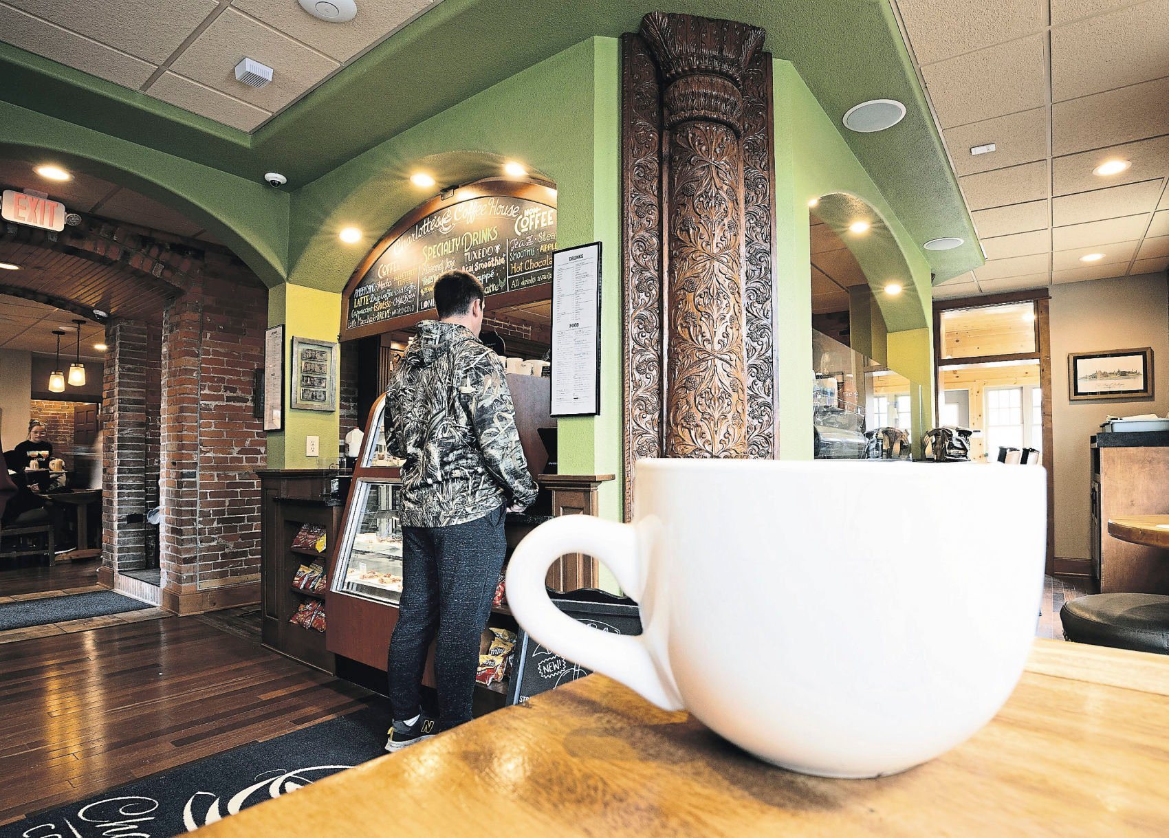A customer looks over the menu at Charlotte’s Coffee House. It is one of the many locally owned coffee shops in Dubuque.    PHOTO CREDIT: Stephen Gassman