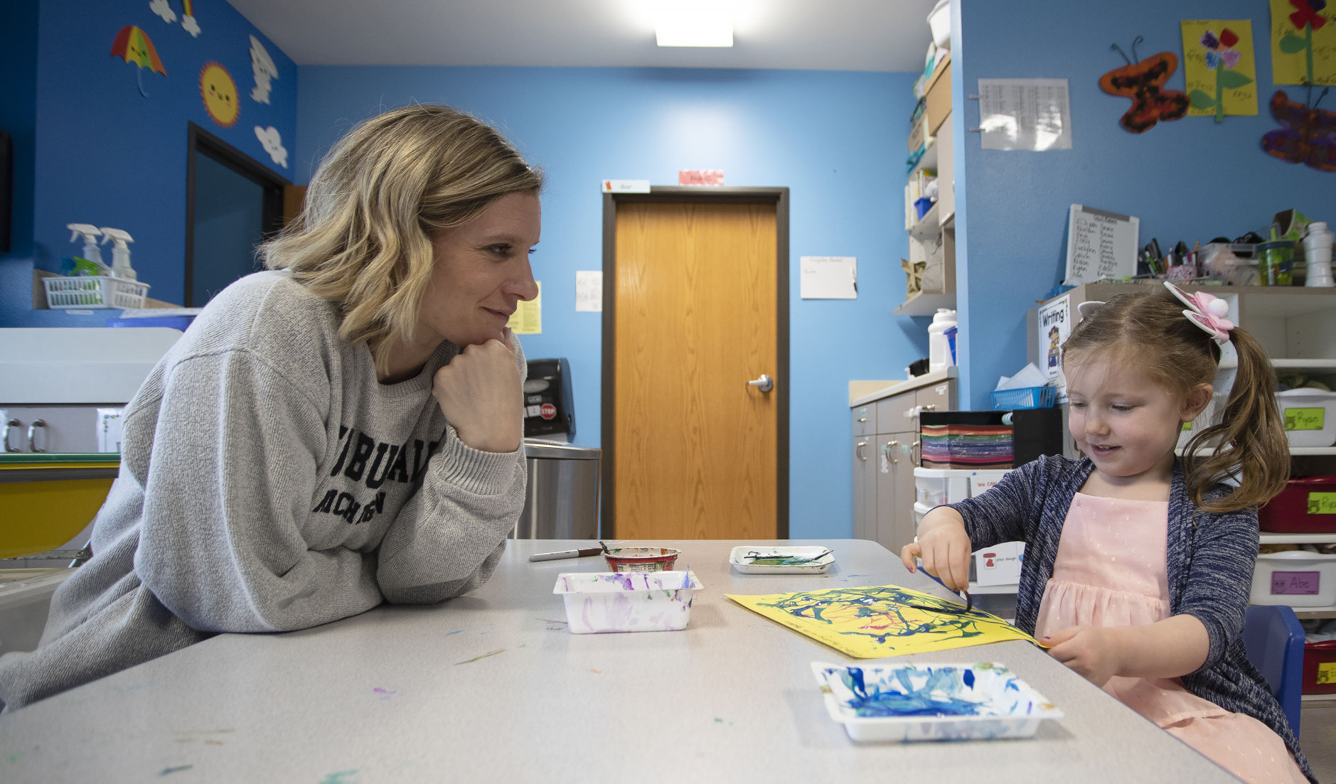 Young-Uns teacher Nicole Thill watches as Eden Peterson, 3, paints at Young-Uns Child Care on Monday, April 18, 2022.    PHOTO CREDIT: Stephen Gassman