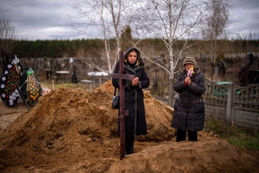 Vera Ptitsyna, 63, right, stands with her daughter Olena, 45, as she mourns on her husband