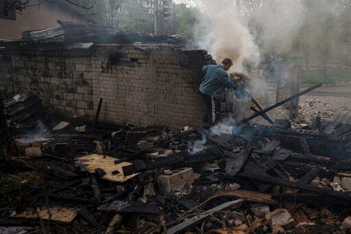 A man tries to extinguish a fire following a Russian bombardment at a residential neighborhood in Kharkiv, Ukraine, Tuesday, April 19, 2022. (AP Photo/Felipe Dana)    PHOTO CREDIT: Felipe Dana