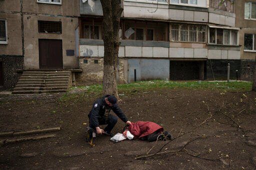 A police officer checks the body of a woman killed during a Russian bombardment at a residential neighborhood in Kharkiv, Ukraine, Tuesday, April 19, 2022. Russia ratcheted up its battle for control of Ukraine’s eastern industrial heartland on Tuesday, intensifying assaults on cities and towns along a front hundreds of miles long in what officials on both sides described as a new phase of the war. (AP Photo/Felipe Dana)    PHOTO CREDIT: Felipe Dana