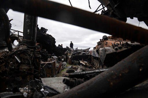 A local man stands atop of destroyed Russian armoured vehicles in Bucha, Ukraine, Tuesday, April 19, 2022. (AP Photo/Evgeniy Maloletka)    PHOTO CREDIT: Evgeniy Maloletka