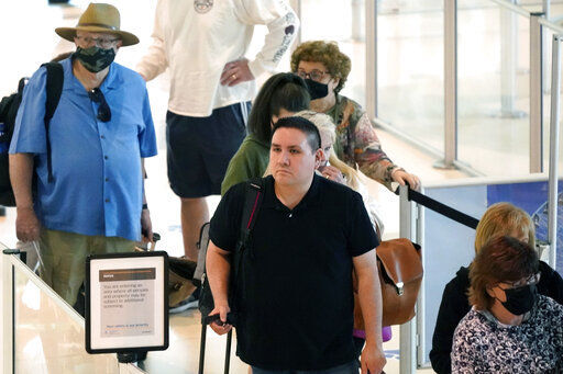 Travelers wait in a security line at Love Field in Dallas Tuesday. The major airlines and many of the busiest airports dropped their mask requirements after a Florida judge struck down the CDC mandate and the Transportation Security Administration announced it wouldn