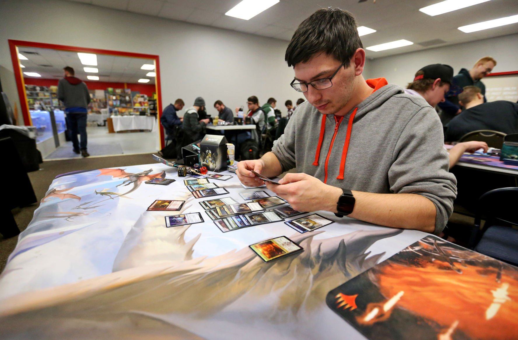 Spencer Hummel, of Asbury, Iowa, sort cards at Comic World & Games in Dubuque on Friday, April 22, 2022. The business recently added 2,000 more square feet of space for in-person gaming.    PHOTO CREDIT: JESSICA REILLY