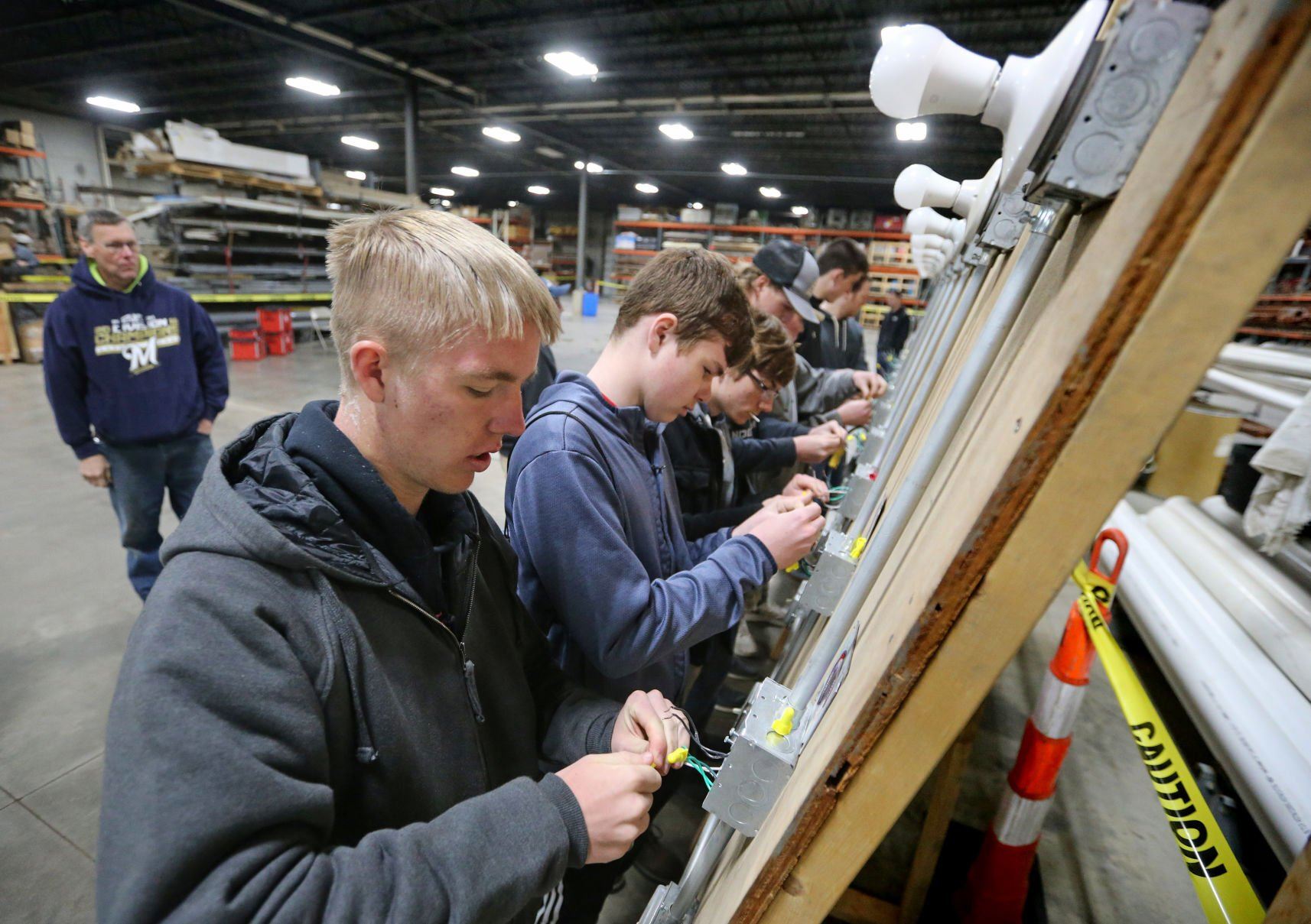 Gabe Mennig (left), 18, of Platteville, Wis., works to splice a junction box during the Construction Industry Career Expo at Portzen Construction in Dubuque on Thursday, April 28, 2022.    PHOTO CREDIT: JESSICA REILLY