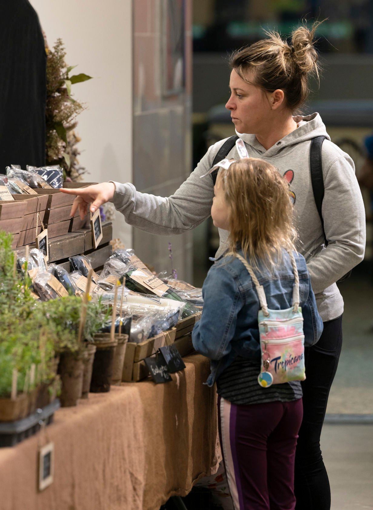 Jessica Flatin and her daughter Charley shop at Dobie’s stand during the winter farmers market at Kennedy Mall in April.    PHOTO CREDIT: Stephen Gassman