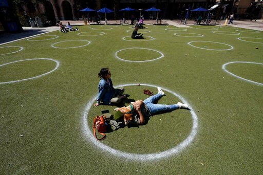 FILE - Kyree Kayoshi, his dog Kumi, and Miranda De Llano use circles marked for social distancing to help battle the COVID-19 virus as they relax at the Pearl Brewery, March 3, 2021, in San Antonio. The U.S. death toll from COVID-19 has hit 1 million, less than 2 1/2 years into the outbreak. (AP Photo/Eric Gay, File)    PHOTO CREDIT: Eric Gay
