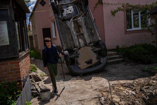 A resident carries a shovel to clear the rubble from his house damaged during a shelling in Kharkiv, Ukraine, Monday, May 16, 2022. (AP Photo/Bernat Armangue)    PHOTO CREDIT: Bernat Armangue