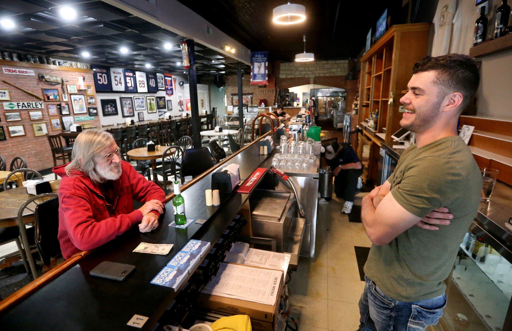 Owner Jacob Schroeder (right) talks with Bill Einwalter, of Farley, Iowa, at Bill’s Tap in Farley on Wednesday.    PHOTO CREDIT: JESSICA REILLY