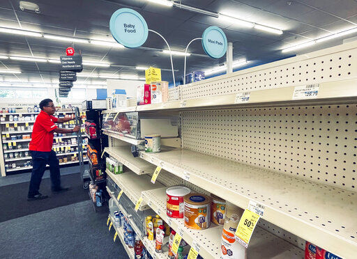 An employee walks near empty shelves where baby formula would normally be located at a CVS in New Orleans on Monday, May 16, 2022. President Joe Biden
