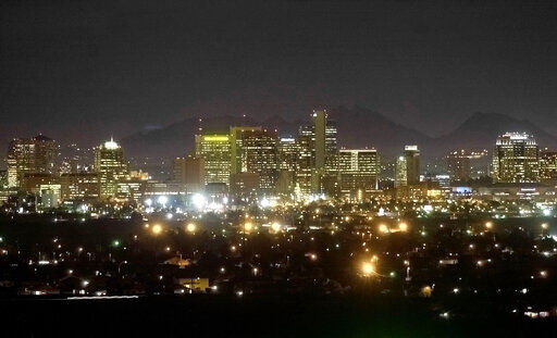 FILE - Piestewa Peak is seen behind the illuminated Phoenix skyline on February 28, 2002, from South Mountain in Phoenix. Eight of the 10 largest cities in the U.S. lost population during the first year of the pandemic, with only Phoenix and San Antonio gaining new residents from 2020 to 2021, according to new estimates released, Thursday, May 26, 2022, by the U.S. Census Bureau. (AP Photo/Mel Evans, File)    PHOTO CREDIT: Mel Evans