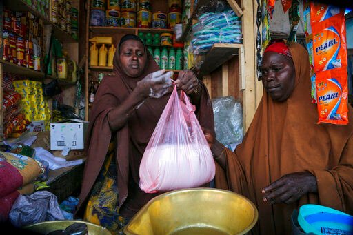 Halimo Hersi, 42, right, buys wheat flour from a shopkeeper in the Hamar-Weyne market in the capital Mogadishu, Somalia Thursday, May 26, 2022. Families across Africa are paying about 45% more for wheat flour as Russia