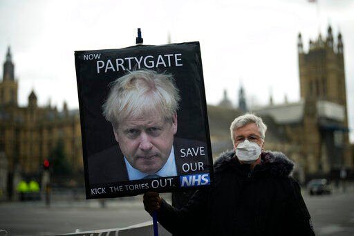 FILE - An anti-Conservative Party protester holds a placard with an image of British Prime Minister Boris Johnson including the words "Now Partygate" backdropped by the Houses of Parliament, in London, Wednesday, Dec. 8, 2021. Britain’s governing Conservatives will hold a no-confidence vote in Prime Minister Boris Johnson on Monday, June 6, 2022 that could oust him as Britain’s leader. Johnson has been struggling to turn a page on months of ethics scandals, most notably over rule-breaking parties in government buildings during COVID-19 lockdowns. (AP Photo/Matt Dunham, File)    PHOTO CREDIT: Matt Dunham