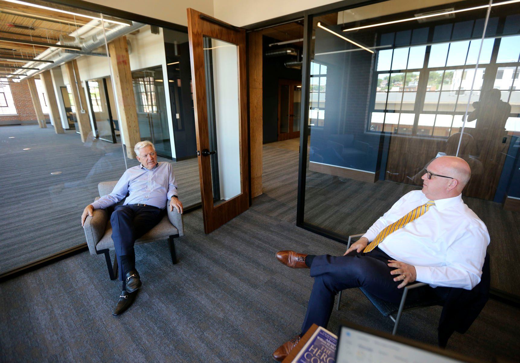 Steele Capital Management CEO Michael Steele (left) talks with company President Michael Doyle in its new location at the Dupaco Voices Building at 1000 Jackson St.    PHOTO CREDIT: Dave Kettering