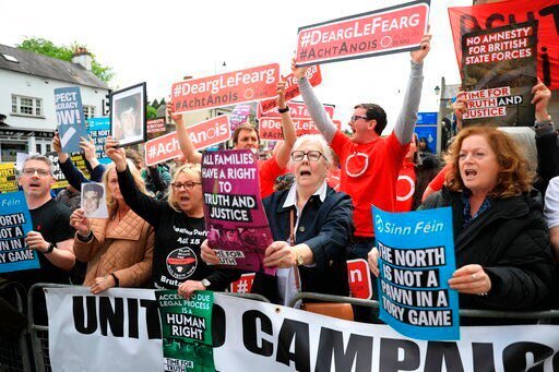 FILE - Demonstrators hold up signs including in Irish reading "Red with Anger, Act now", as they protest outside Hillsborough Castle, ahead of a visit by British Prime Minister Boris Johnson, in Hillsborough, Northern Ireland, Monday, May, 16, 2022. Britain’s government is expected to introduce legislation that would unilaterally change post-Brexit trade rules for Northern Ireland amid opposition from lawmakers who believe the move violates international law. The legislation, expected Monday, June 13, 2022, would let the government bypass the so-called Northern Ireland Protocol, which requires the inspection of some goods shipped there from other parts of the United Kingdom. (AP Photo/Peter Morrison, File)    PHOTO CREDIT: Peter Morrison