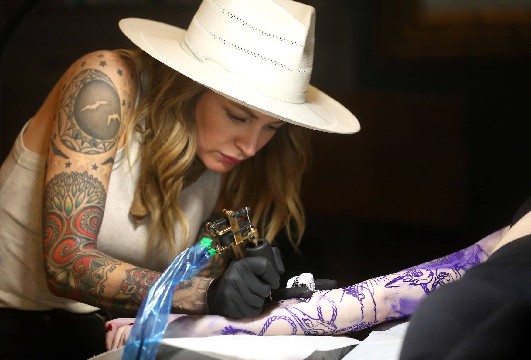 Owner Sarah Anderson tattoos Chelsey Shone, of Fayetteville, Ark., at Goldies in Dubuque.    PHOTO CREDIT: JESSICA REILLY