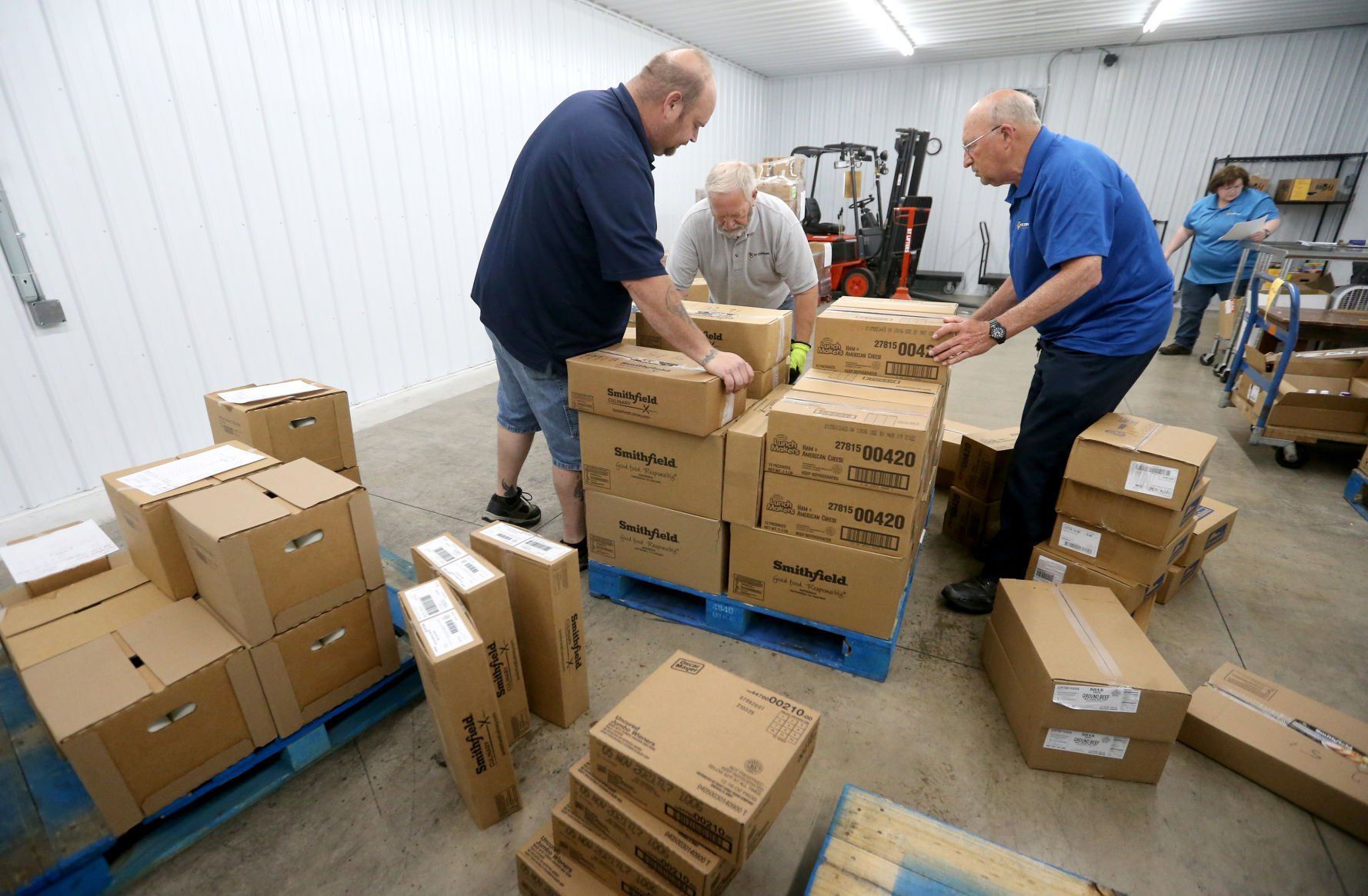Josh Engelkins (from left), Tom Paisley and Larry Griffin sort a pallet of food at St. Stephen’s Food Bank, a branch of River Bend Food Bank, in Dubuque on Tuesday.    PHOTO CREDIT: JESSICA REILLY