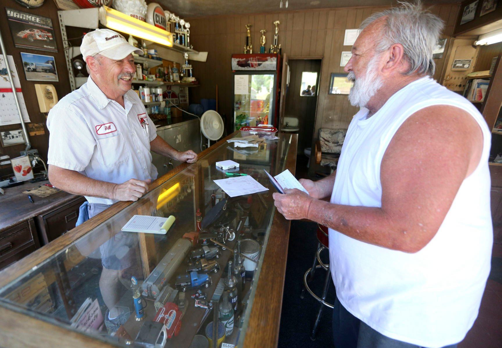 Bill Bowman (left), the owner of Bowman Oil Co., chats with longtime customer Everett Bowling, of Maquoketa, Iowa, on Wednesday, June 29, 2022. The gas station closed its doors for good on Thursday.    PHOTO CREDIT: Dave Kettering