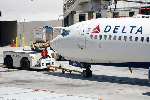 A tug driver pushes a Delta Air Lines Boeing 737 back from a gate, Thursday, July 7, 2022, at the Fort Lauderdale-Hollywood International Airport in Fort Lauderdale, Fla. Delta Air Lines said Wednesday, July 13, 2022, that it earned $735 million in the second quarter. Earnings per share fell short of Wall Street expectations, however, which the airline blamed on high fuel prices and more than 4,000 canceled flights in May and June. (AP Photo/Wilfredo Lee)    PHOTO CREDIT: Wilfredo Lee