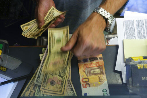 A cashier changes a 50 Euro banknote with US dollars at an exchange counter in Rome. Europe