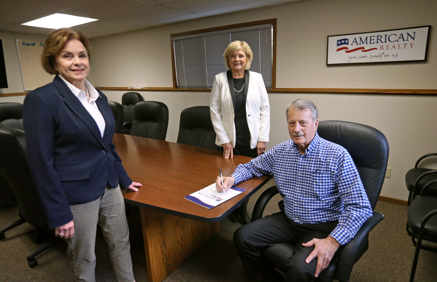 Peggy Nesler (from left), Shari Greenwood and Bob Neuwoehner gather in a boardroom at American Realty in Dubuque.    PHOTO CREDIT: JESSICA REILLY
