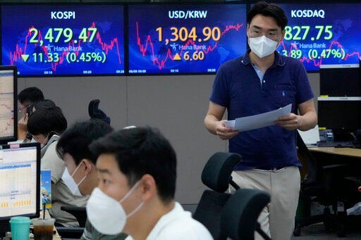 A currency trader passes by screens showing the Korea Composite Stock Price Index (KOSPI), left, and the exchange rate of South Korean won against the U.S. dollar, center, at the foreign exchange dealing room of the KEB Hana Bank headquarters in Seoul, South Korea, Monday, Aug. 8, 2022. Asian stocks were mixed Monday after strong U.S. jobs data cleared the way for more interest rate hikes and Chinese exports rose by double digits. (AP Photo/Ahn Young-joon)    PHOTO CREDIT: Ahn Young-joon