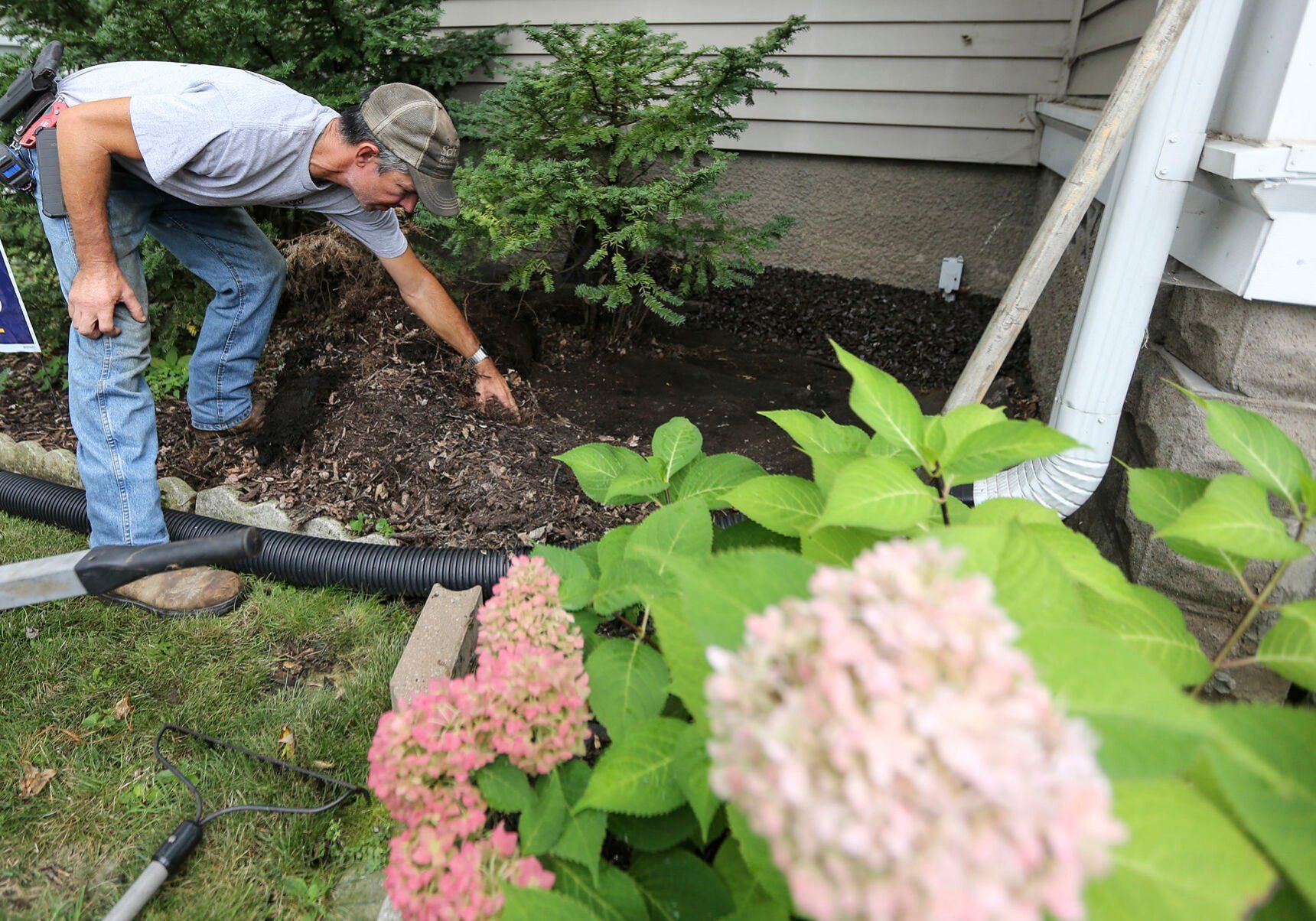 Chuck Schueller, of Epworth, Iowa, owner of Schueller Services LLC, installs mulch around a home in Dubuque on Thursday. Schueller has seen rising fuel costs eating into his profit margin.    PHOTO CREDIT: Dave Kettering