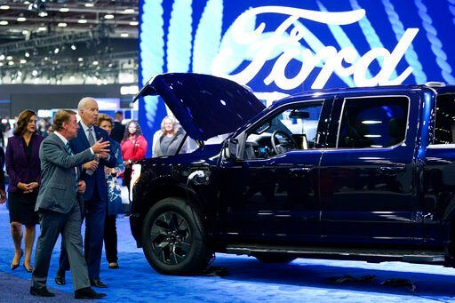 President Joe Biden listens as Bill Ford, executive chairman of Ford Motor Company, speaks during a tour at the Detroit Auto Show, Wednesday, Sept. 14, 2022, in Detroit. Michigan Gov. Gretchen Whitmer is at left. (AP Photo/Evan Vucci)    PHOTO CREDIT: Evan Vucci