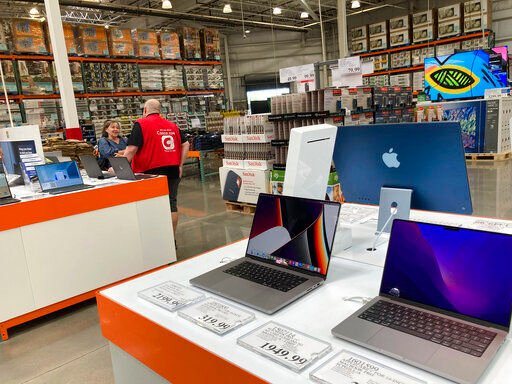 A sales associate helps a prospective customer as laptops sit on display in a Costco warehouse. Americans picked up their spending a bit in August from July even as surging inflation on household necessities like rent and food take a toll on household budgets.    PHOTO CREDIT: David Zalubowski