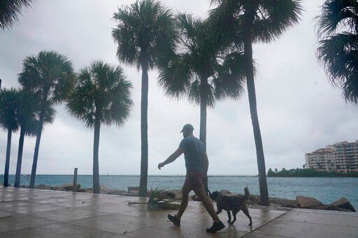 A man walks his dog during a break of heavy rain, Tuesday, Sept. 27, 2022, in Miami Beach, Fla. Hurricane Ian is expected to make landfall on the west coast of Florida. (AP Photo/Marta Lavandier)    PHOTO CREDIT: Marta Lavandier
