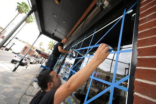 Lukas Berlajolli, above, and Tony Fazliu help tape up the windows of a pizza restaurant in the Ybor City district in preparation for Hurricane Ian as the storm approaches the western side of the state, Tuesday, Sept. 27, 2022, in Tampa, Fla. (AP Photo/Phelan M. Ebenhack)    PHOTO CREDIT: Phelan M. Ebenhack