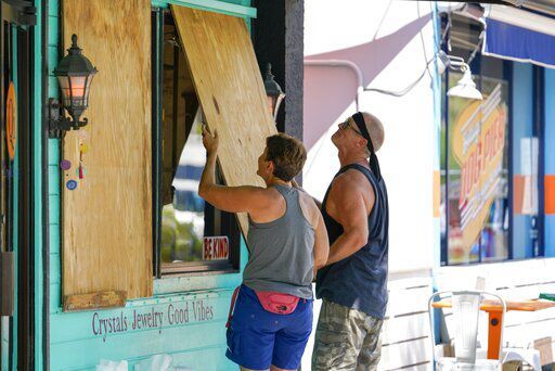 FILE - Lisa Bromfield and Mike Sernett work to place a sheet of plywood on the front windows of a store in downtown Gulfport in preparation for the arrival of Hurricane Ian, Sept. 26, 2022, in South Pasadena, Fla. Hurricane Ian is quickly gaining monstrous strength as it moves over oceans partly heated up by climate change. (Martha Asencio-Rhine/Tampa Bay Times via AP, File)    PHOTO CREDIT: Martha Asencio-Rhine
