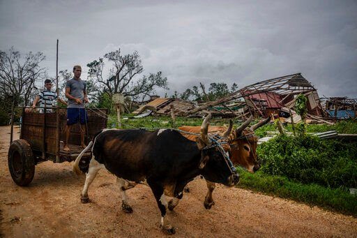 Men lead their ox cart past a tobacco warehouse smashed by Hurricane Ian in Pinar del Rio, Cuba, Tuesday, Sept. 27, 2022. Hurricane Ian tore into western Cuba as a major hurricane and left 1 million people without electricity, then churned on a collision course with Florida over warm Gulf waters amid expectations it would strengthen into a catastrophic Category 4 storm. (AP Photo/Ramon Espinosa)    PHOTO CREDIT: Ramon Espinosa