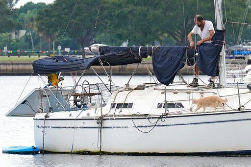 A man, along with his Macaw and cat, prepares his sailboat on the Davis Islands yacht basin ahead of the potential arrival of Hurricane Ian Tuesday, Sept. 27, 2022, in Tampa, Fla. Ian is predicted to make landfall somewhere along Florida