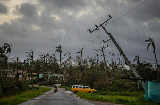 A classic American car drives past utility poles tilted by Hurricane Ian in Pinar del Rio, Cuba, Tuesday, Sept. 27, 2022. (AP Photo/Ramon Espinosa)    PHOTO CREDIT: Ramon Espinosa