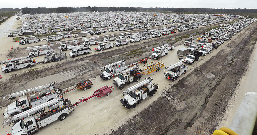 Utility trucks are staged in a rural lot in The Villages of Sumter County, Fla. The U.S. National Hurricane Center says Ian