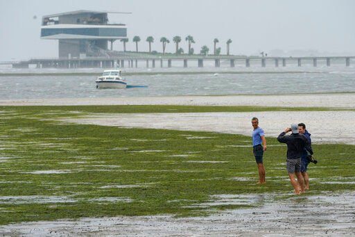 People walk where water is receding out of Tampa Bay due to a negative surge ahead of Hurricane Ian, Wednesday, Sept. 28, 2022, in Tampa, Fla. (AP Photo/Steve Helber)    PHOTO CREDIT: Steve Helber