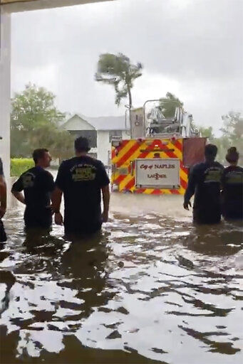 This image provided by the Naples Fire Rescue Department shows firefighters looking out at the firetruck that stands in water from the storm surge from Hurricane Ian on Wednesday, Sept. 28, 2022 in Naples, Fla. Hurricane Ian has made landfall in southwestern Florida as a massive Category 4 storm. (Naples Fire Department via AP)    PHOTO CREDIT: HOGP