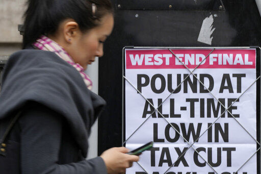A woman walks past a headline posted on a wall in London, Tuesday, Sept. 27, 2022. The British pound has stabilized in Asian trading after plunging to a record low, as the Bank of England and the British government try to soothe markets nervous about a volatile U.K. economy. The instability is having real-world impacts, with several British mortgage lenders withdrawing deals amid concern that interest rates may soon rise sharply. (AP Photo/Frank Augstein)    PHOTO CREDIT: Frank Augstein