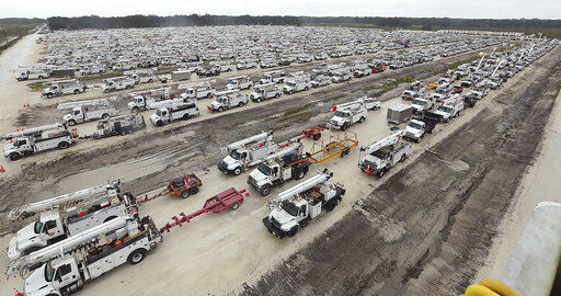 Utility trucks are staged in a rural lot in The Villages of Sumter County, Fla., Wednesday, Sept. 28, 2022. Hurricane Ian rapidly intensified as it neared landfall along Florida