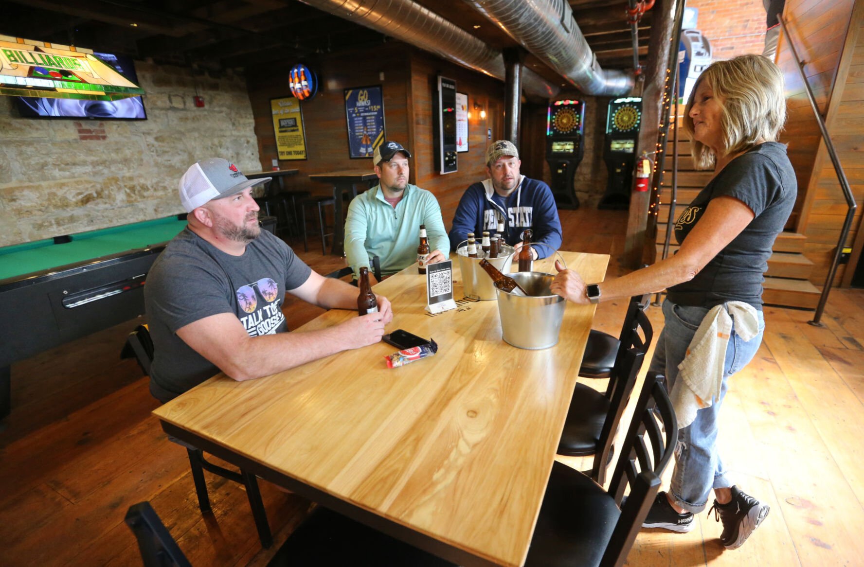 Co-owner Laurie Paulsen talks with Joe Goedken (from left), of Ottumwa, Iowa, and brothers Dan Loud and Kevin Loud, both of Fox Lake, Ill., at The Dungeon in Dubuque.    PHOTO CREDIT: JESSICA REILLY