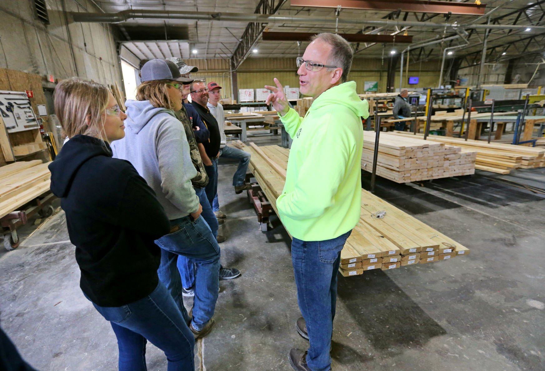 Junior Lainey Knipper (left) and other Maquoketa Valley High School students listen to Bob Stewart, operations manager at Lumber Specialties, during a tour of the facility in Dyersville, Iowa, on Thursday, Oct. 6, 2022, as part of Manufacturing Day sponsored by Dyersville Economic Development.    PHOTO CREDIT: JESSICA REILLY