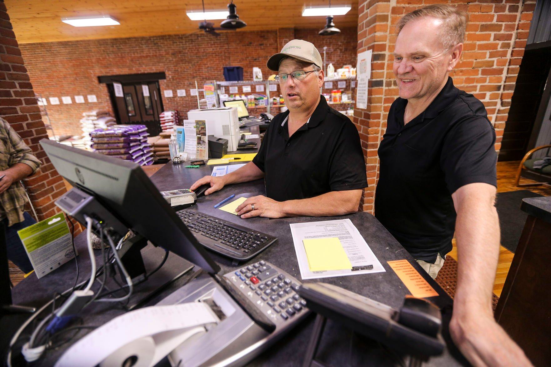 The longtime owner of Hendricks Feed & Seed Co., Bill Hendricks (right), works with new owner Rodney Schroeder at the front desk of the Dubuque business on Wednesday.    PHOTO CREDIT: Dave Kettering