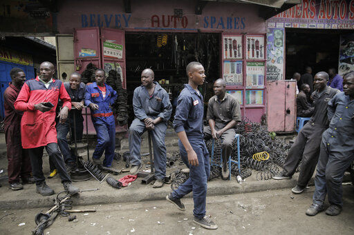 Workers gather as they wait for customers outside a secondhand car parts shop in the industrial area of the capital Nairobi, Kenya. As the value of the U.S. dollar soars, other currencies around the world are sinking by comparison. This is contributing to skyrocketing prices for everyday goods and services and compounding financial distress, especially in poorer countries.     PHOTO CREDIT: Brian Inganga