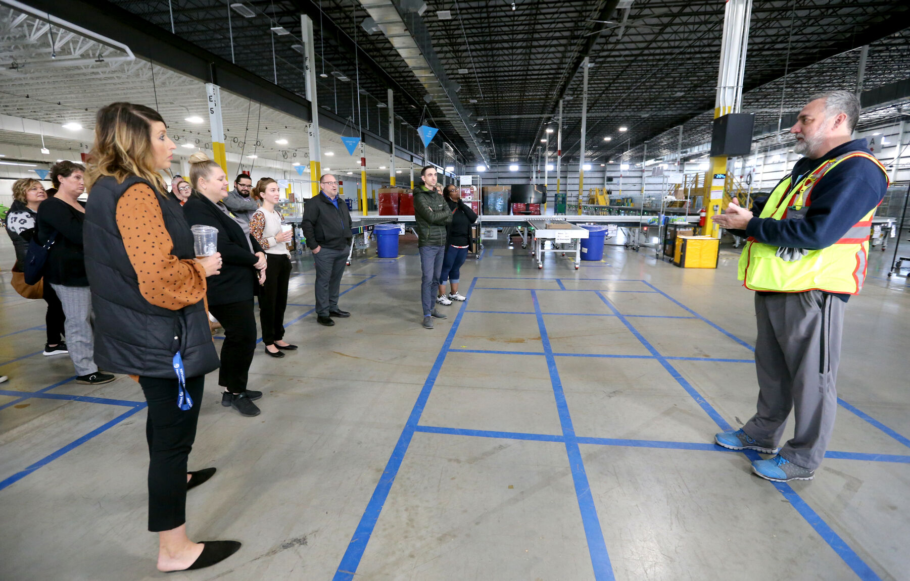 Rob Gruber (far right), a manager at Amazon, gives a tour of the facility in Dubuque on Thursday, Oct. 20, 2022. Iowa Vocational Rehabilitation Services hosted a tour of local businesses that hire people with disabilities as part of National Disability Employment Awareness Month.    PHOTO CREDIT: JESSICA REILLY
